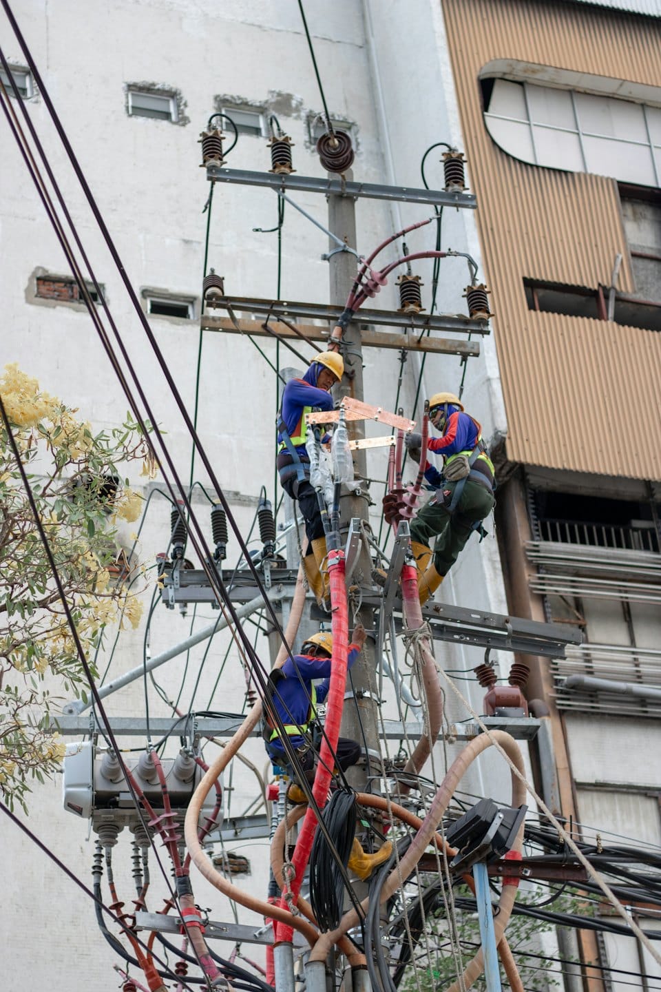 Elektrikári v ochranných odevech pripájajú káble na stĺpe.