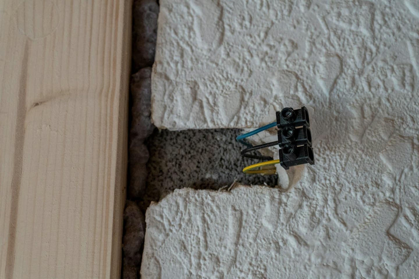 Elektrikár inštaluje modré a žlté káble do steny.